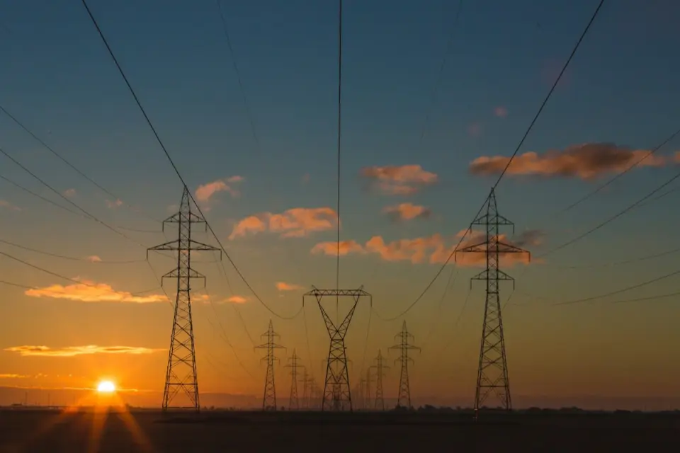 Torres de alta tensión recortadas contra el cielo al atardecer